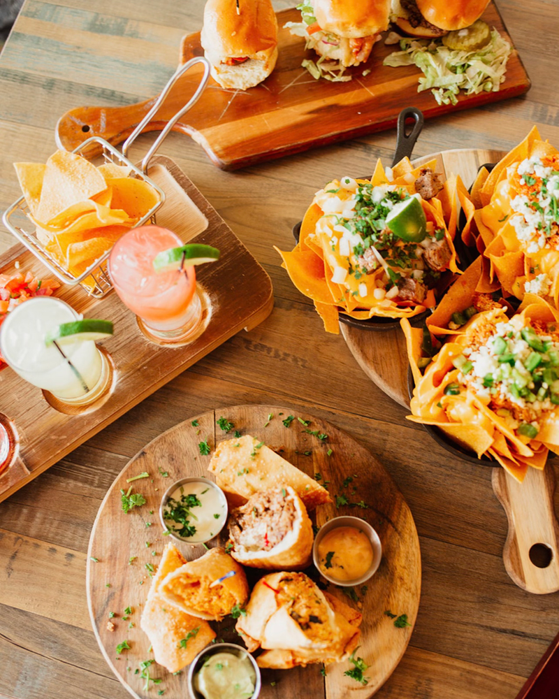 Taco flight on a wooden board with nachos